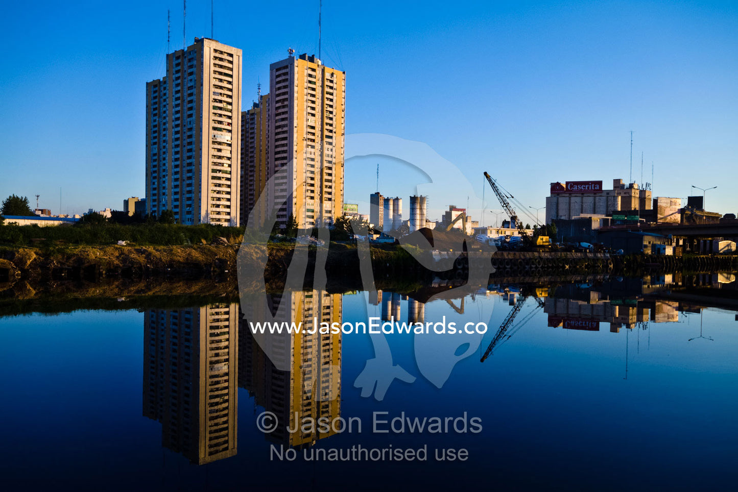 Low income apartment blocks reflected on the still surface of a river. Riachuelo River, La Boca, Buenos Aires, Argentina
