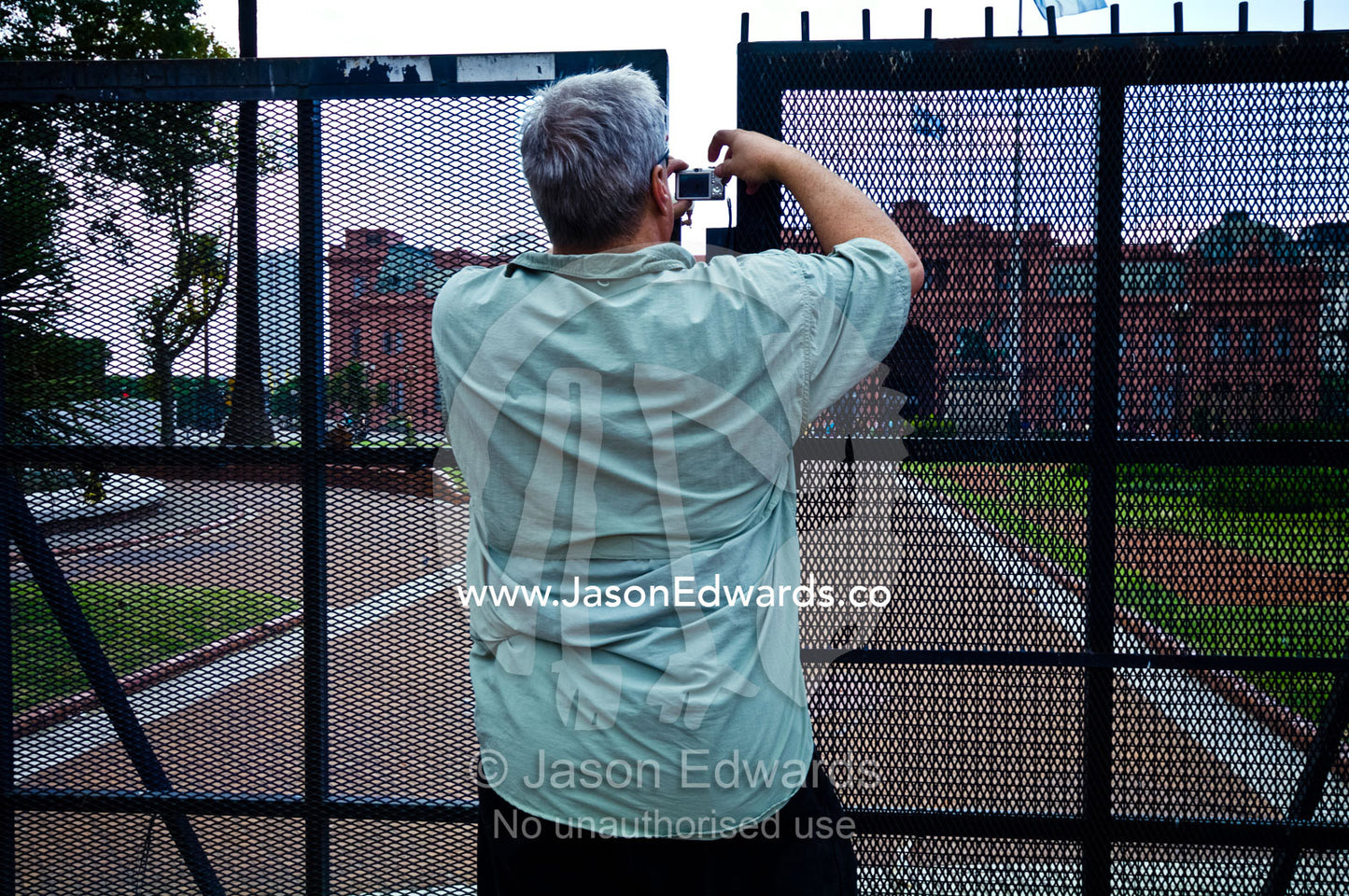 A tourist photographs the Casa Rosada through a steel security fence. Plaza de Mayo, Buenos Aires, Argentina.