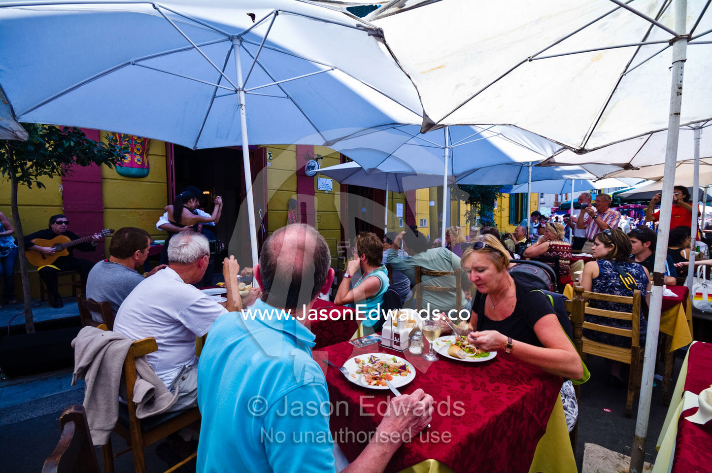 Tourists dine at a restaurant whilst watching Tango dancers perform. La Boca, Buenos Aires, Argentina.