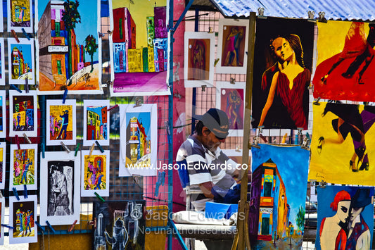 A market stall displays colorful paintings featuring Tango dancers. El Caminito, La Boca, Buenos Aires, Argentina.