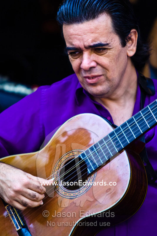 A musician strums an acoustic guitar creating rhythm for Tango dancers El Caminito, La Boca, Buenos Aires, Argentina.