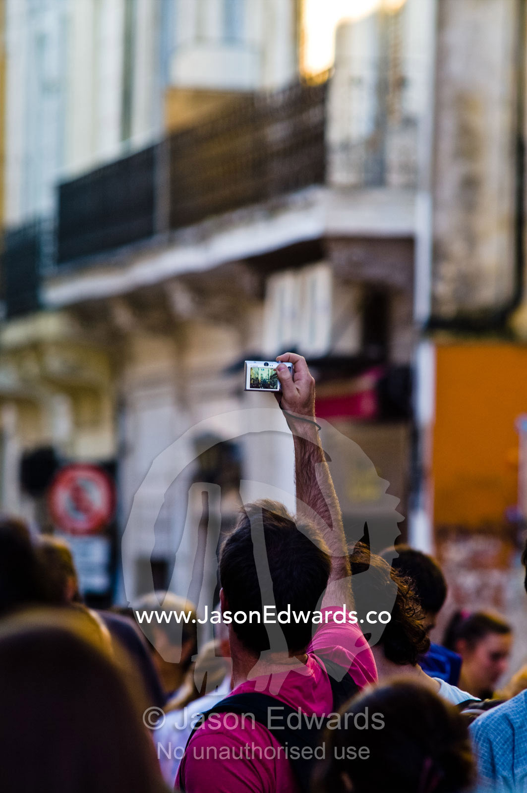 A tourist holds a digital camera above the crowd in a city market. Calle Defensa, San Telmo, Buenos Aires, Argentina.