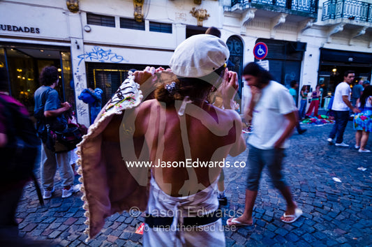 A vendor displays her craft to passing tourists in a city street. Calle Defensa, San Telmo, Buenos Aires, Argentina.