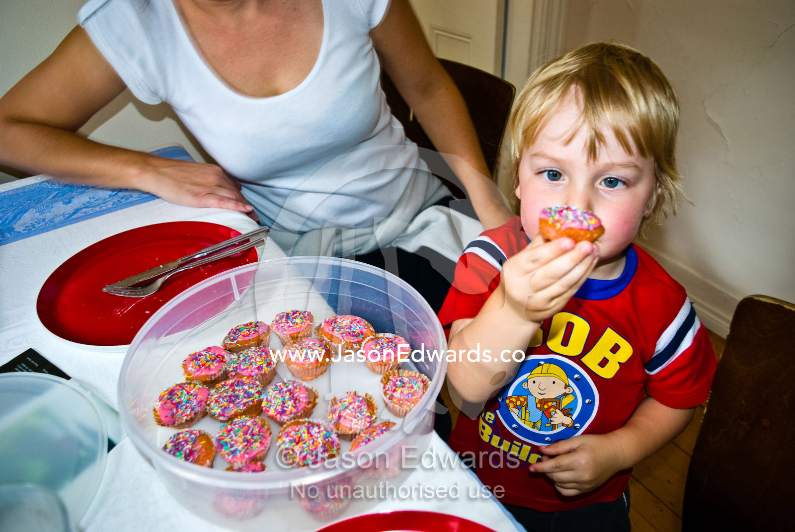 A small boy displays a cupcake covered in colourful candy sprinkles. Carlton North, Melbourne, Victoria, Australia.
