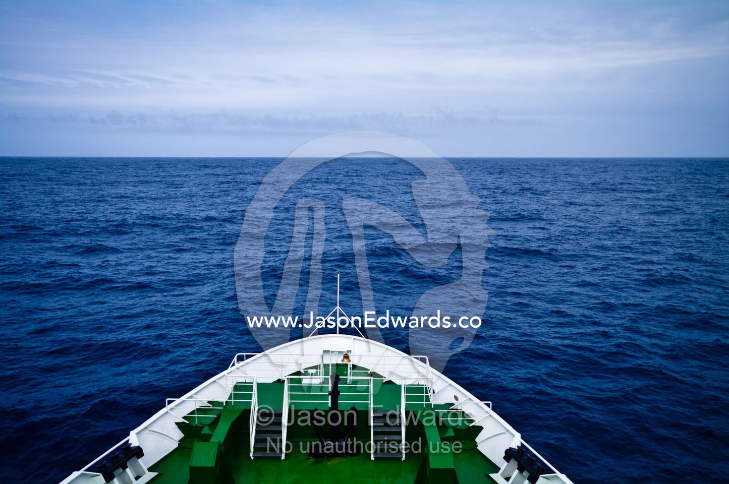 The bow of a ship heading towards a vast and distant ocean horizon. The Drake Passage between the Atlantic Ocean and Pacific Ocean.