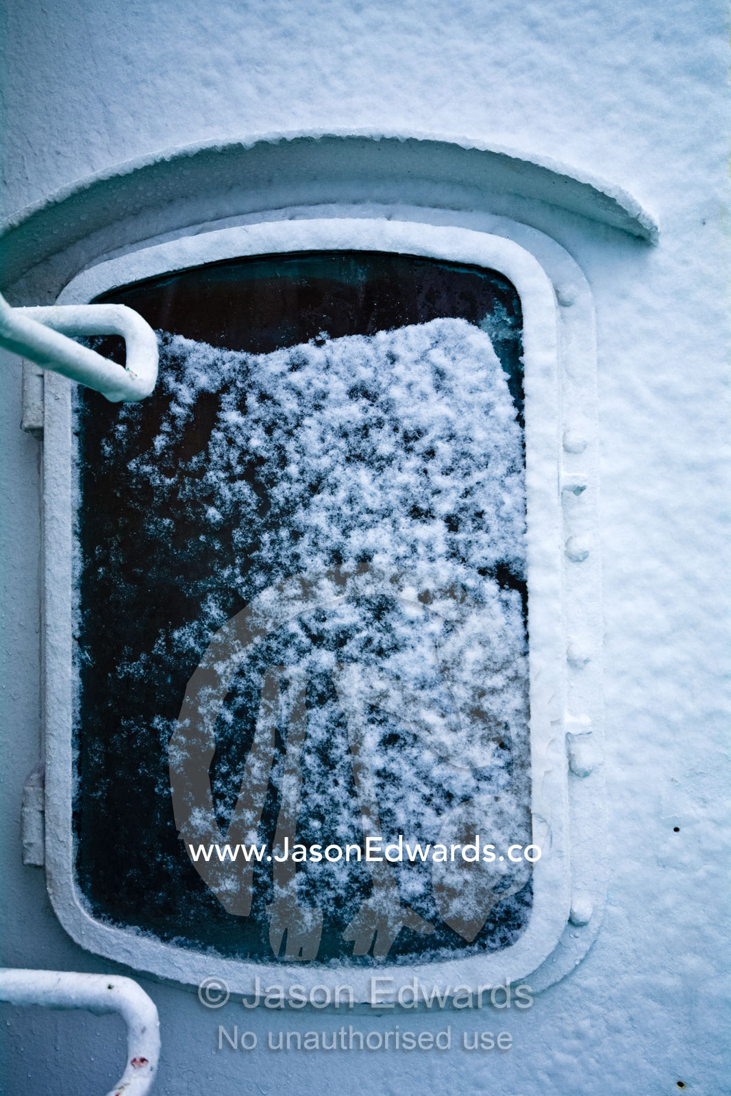 Snow and ice gather on porthole glass in a ship heading to Antarctica. The Drake Passage between the Atlantic Ocean and Pacific Ocean.