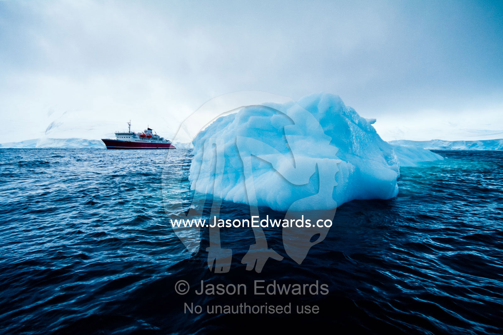 An ecotourism ship moored near an iceberg below the Antarctic Circle. Crystal Sound, Hanusse Bay, Antarctic Peninsula, Antarctic Circle, Antarctica.