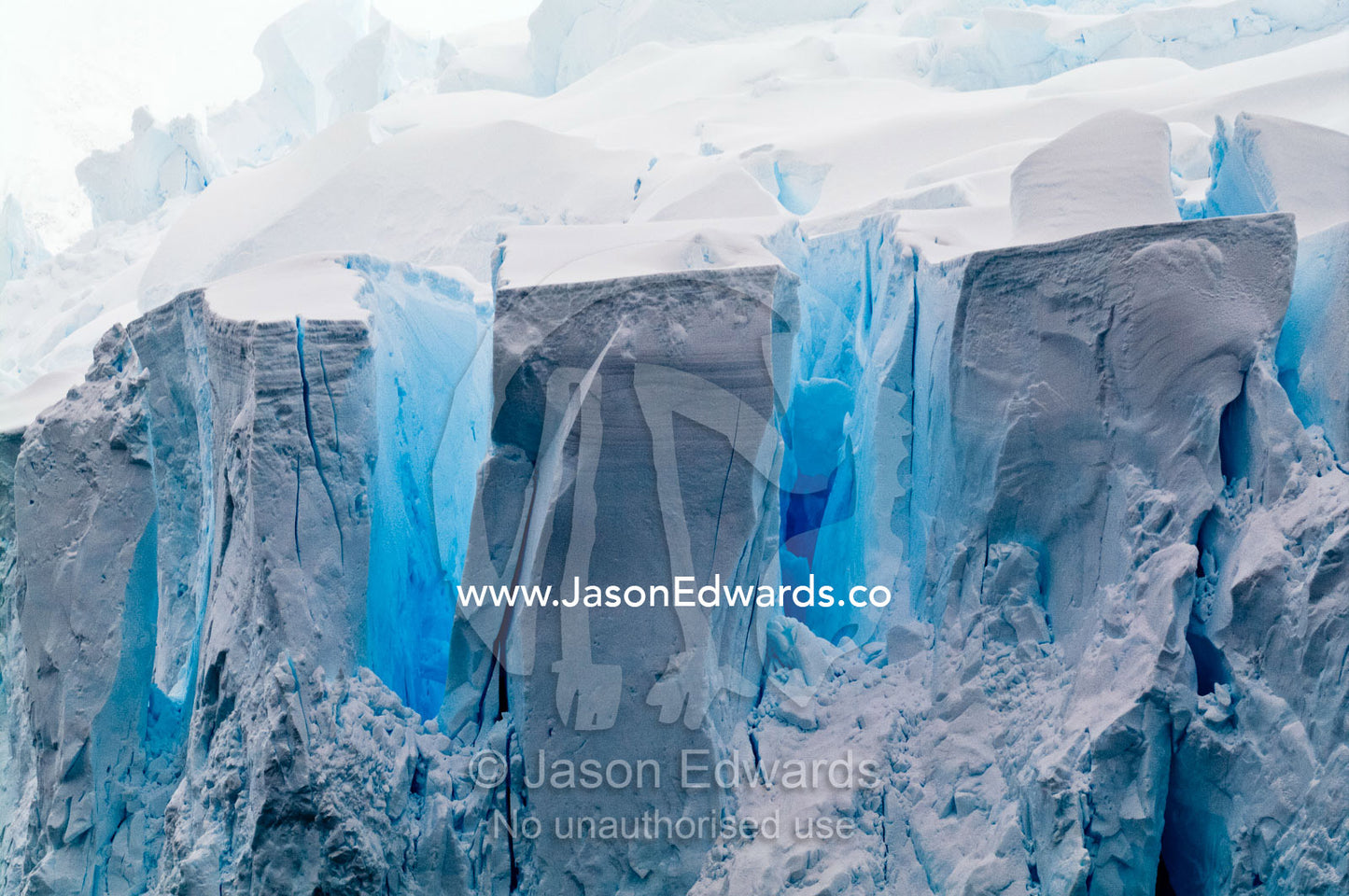 The fracture zone of massive glacial ice cliffs teeter over icy seas. Crystal Sound, Hansen Island, Hanusse Bay, Antarctic Peninsula, Antarctic Circle, Antarctica.