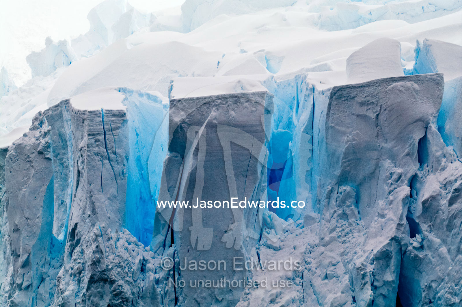 The fracture zone of massive glacial ice cliffs teeter over icy seas. Crystal Sound, Hansen Island, Hanusse Bay, Antarctic Peninsula, Antarctic Circle, Antarctica.