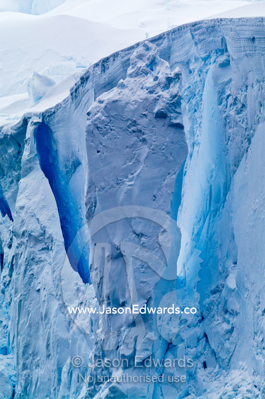 The fracture zone of massive glacial ice cliffs teeter over icy seas. Crystal Sound, Hansen Island, Hanusse Bay, Antarctic Peninsula, Antarctic Circle, Antarctica.