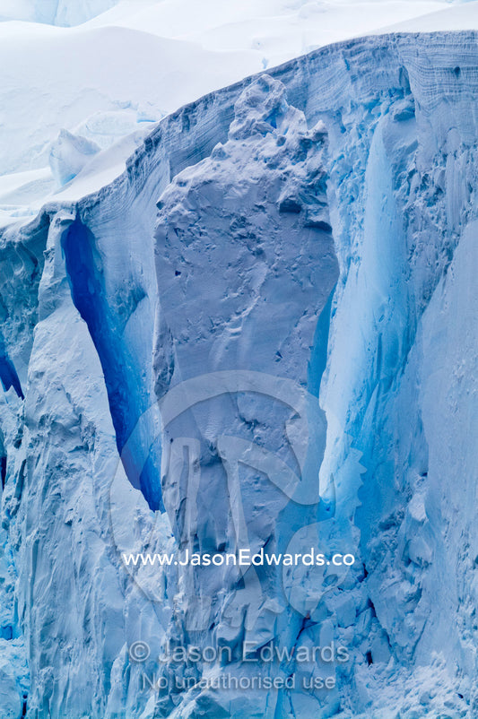The fracture zone of massive glacial ice cliffs teeter over icy seas. Crystal Sound, Hansen Island, Hanusse Bay, Antarctic Peninsula, Antarctic Circle, Antarctica.