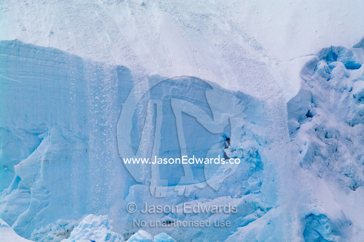 An avalanche of snow and ice flow off the sheer edge of a glacier. Crystal Sound, Hansen Island, Hanusse Bay, Antarctic Peninsula, Antarctic Circle, Antarctica.