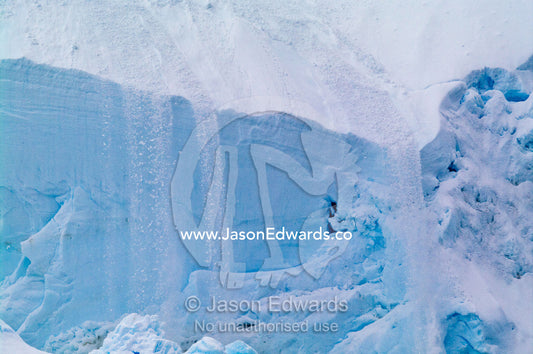 An avalanche of snow and ice flow off the sheer edge of a glacier. Crystal Sound, Hansen Island, Hanusse Bay, Antarctic Peninsula, Antarctic Circle, Antarctica.