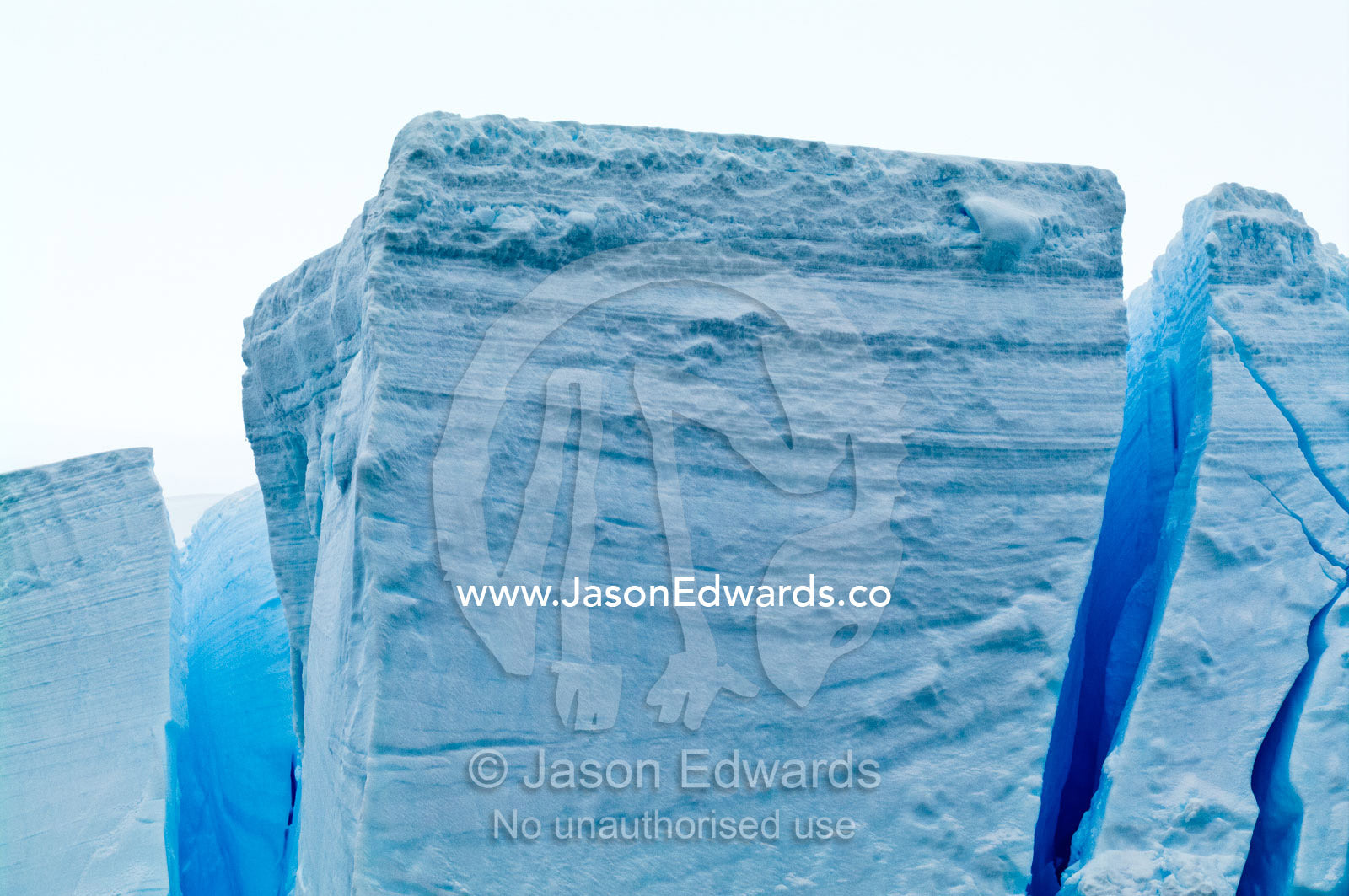 The fracture zone of massive glacial ice cliffs teeter over icy seas. Crystal Sound, Hanusse Bay, Antarctic Peninsula, Antarctic Circle, Antarctica.