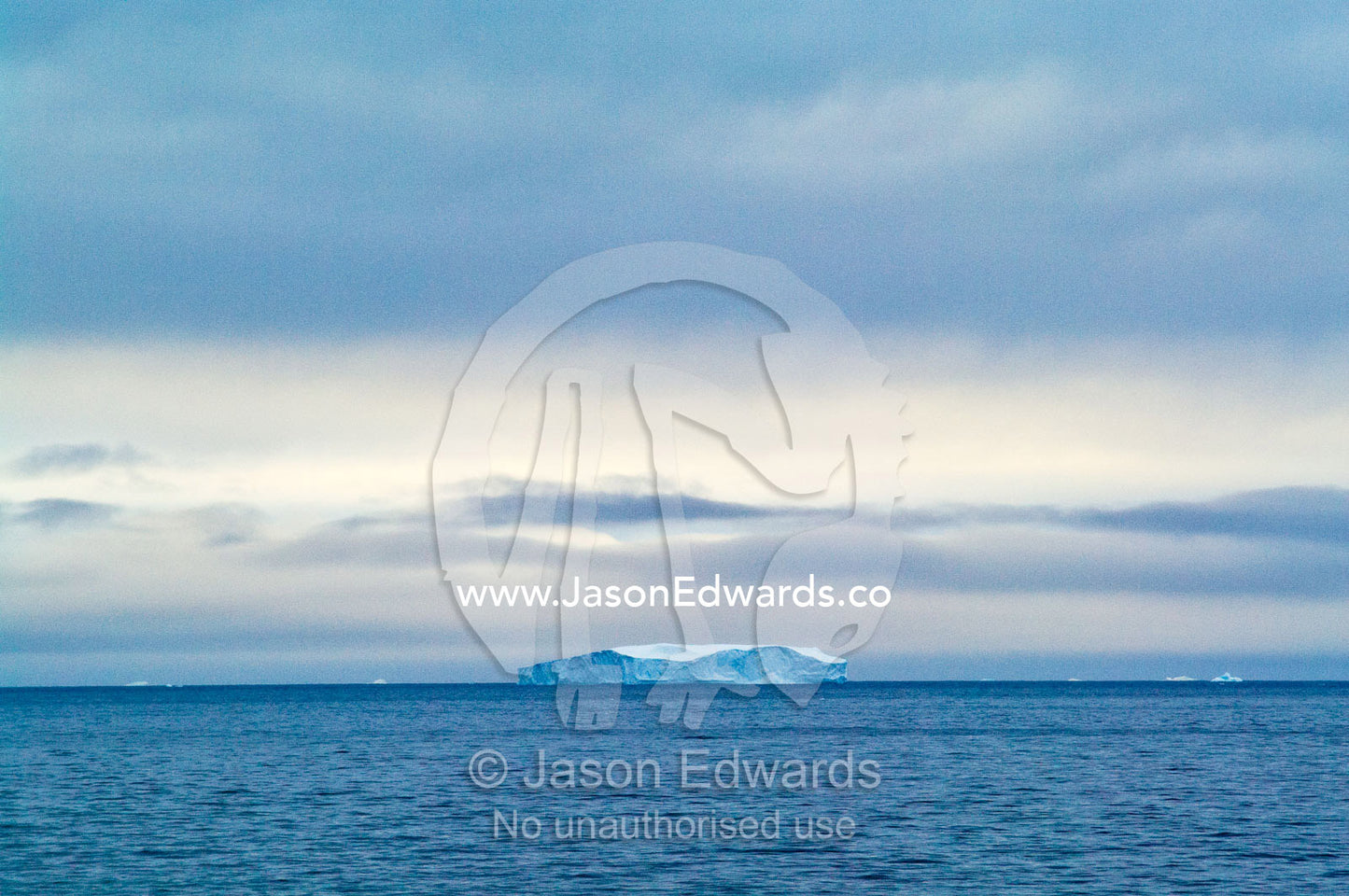 A lone iceberg floating in the open ocean after sunset. Crystal Sound, Antarctic Peninsula, Antarctic Circle, Antarctica.