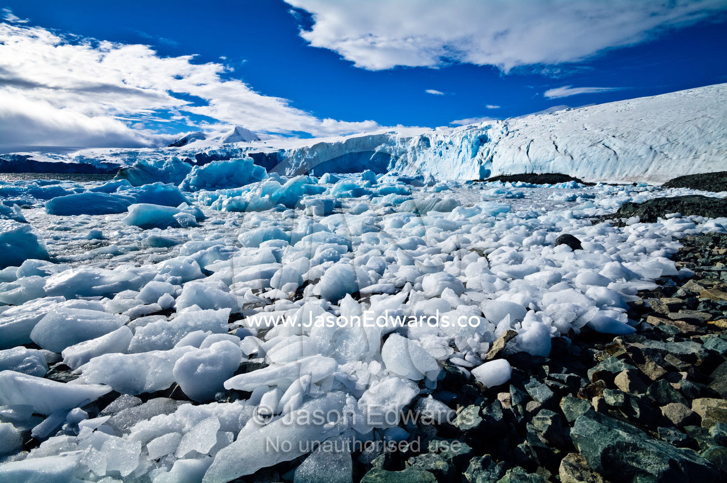 Crushed ice flows and icebergs crowd in a diorite bay near ice cliffs. Prospect Point, Crystal Sound, Antarctic Peninsula, Antarctic Circle, Antarctica.