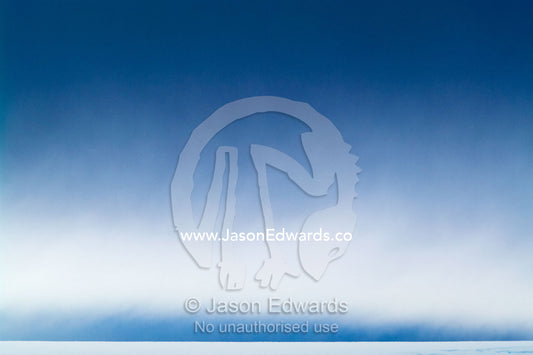 Brooding storm clouds descend over the surface of a flat glacier. Fish Islands, Flouder Island, The Minnows, Crystal Sound, Antarctic Peninsula, Antarctic Circle, Antarctica.