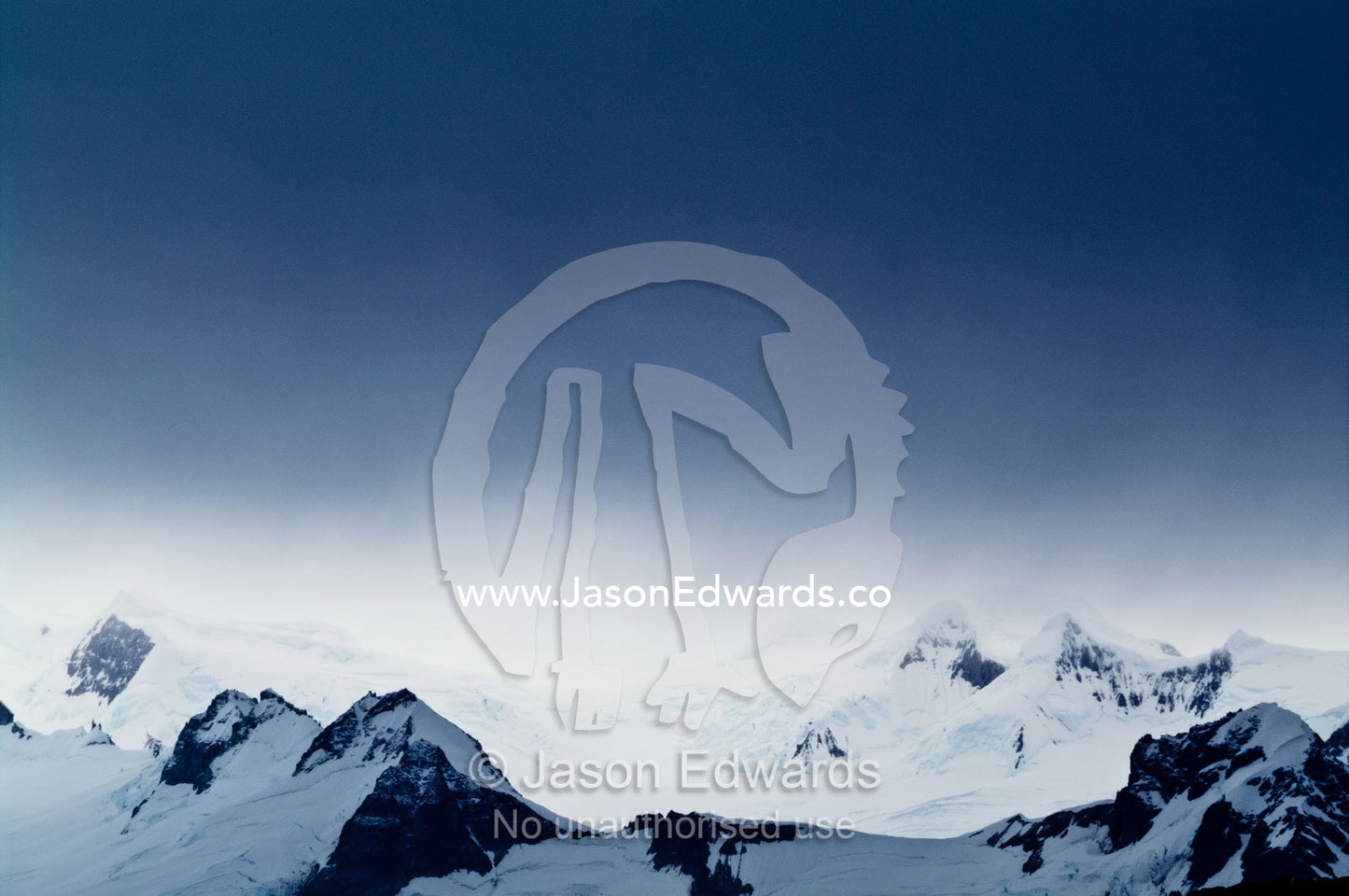 A storm descends over rugged mountain summits covered in snow and ice. Fish Islands, Flouder Island, The Minnows, Crystal Sound, Antarctic Peninsula, Antarctic Circle, Antarctica.