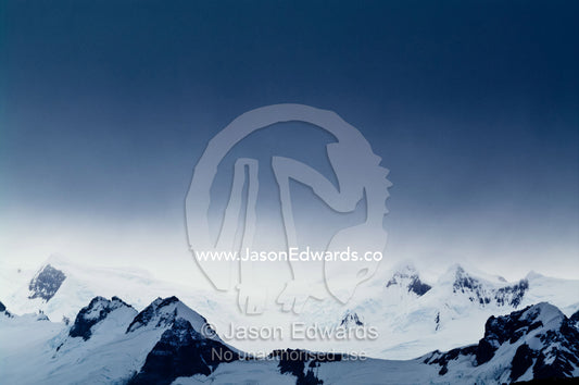 A storm descends over rugged mountain summits covered in snow and ice. Fish Islands, Flouder Island, The Minnows, Crystal Sound, Antarctic Peninsula, Antarctic Circle, Antarctica.