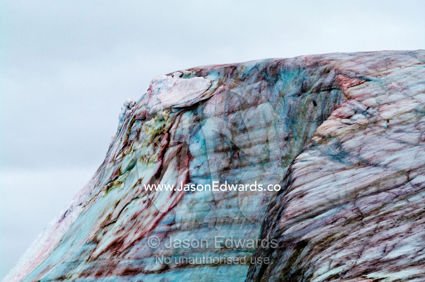 A rugged weathered glacier cap with pink Snow Algae, cryoalgae. Winter Island, Argentine Islands, Faraday Islands, Antarctic Peninsula, Antarctica
