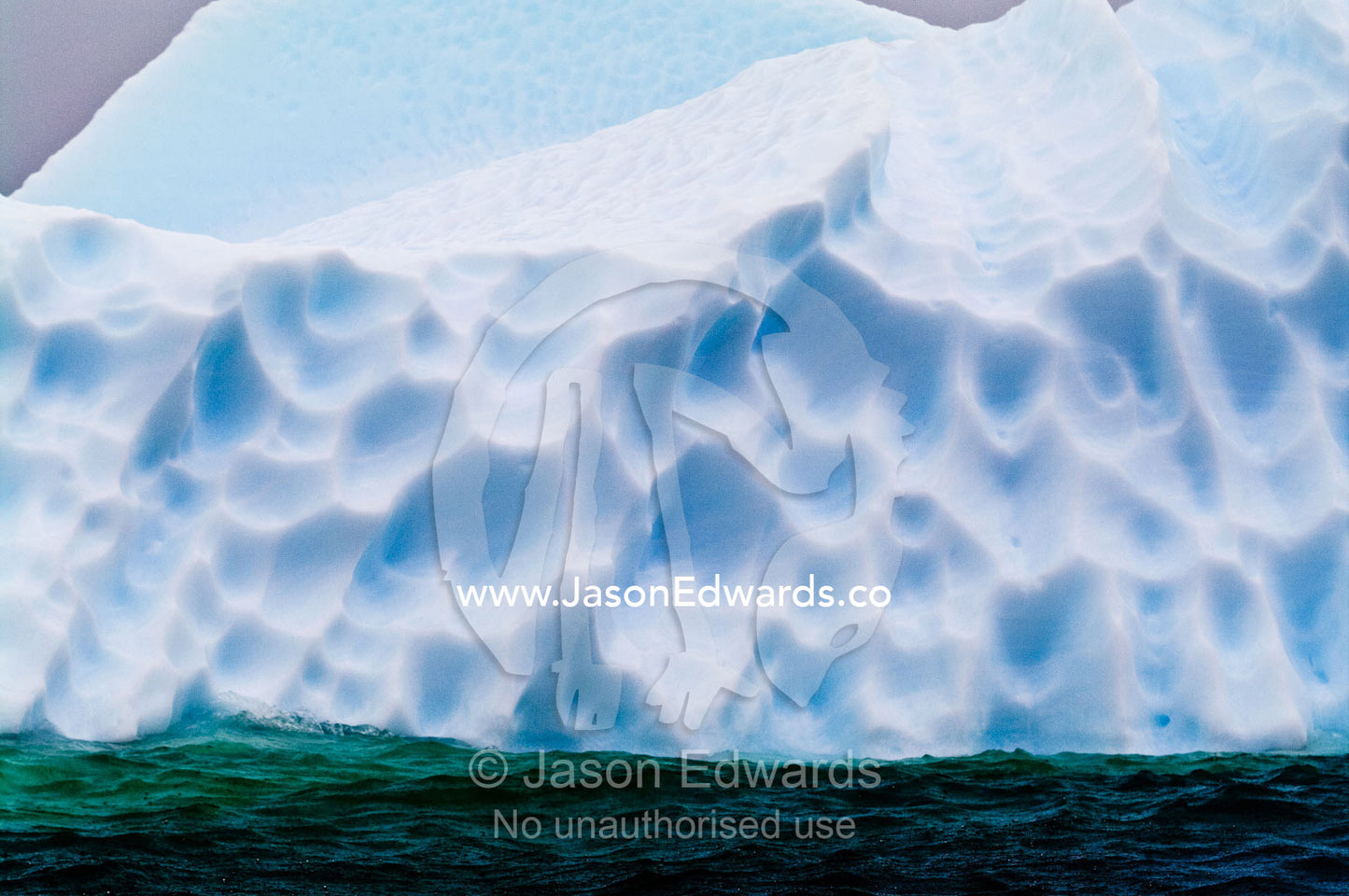 Jagged icebergs rise from a deep green sea beneath a bitter grey sky. Pl��neau and Booth Islands, Bellingshausen Sea, Antarctic Peninsula, Antarctica.
