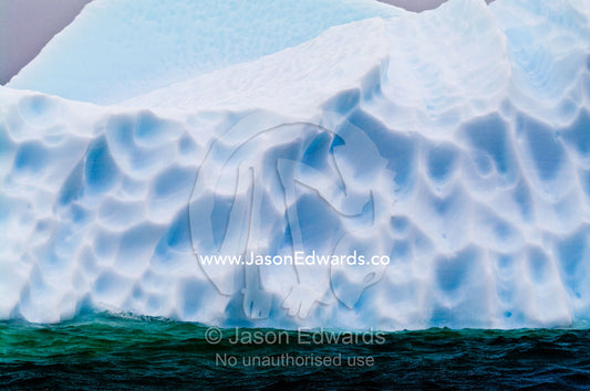 Jagged icebergs rise from a deep green sea beneath a bitter grey sky. Pl��neau and Booth Islands, Bellingshausen Sea, Antarctic Peninsula, Antarctica.