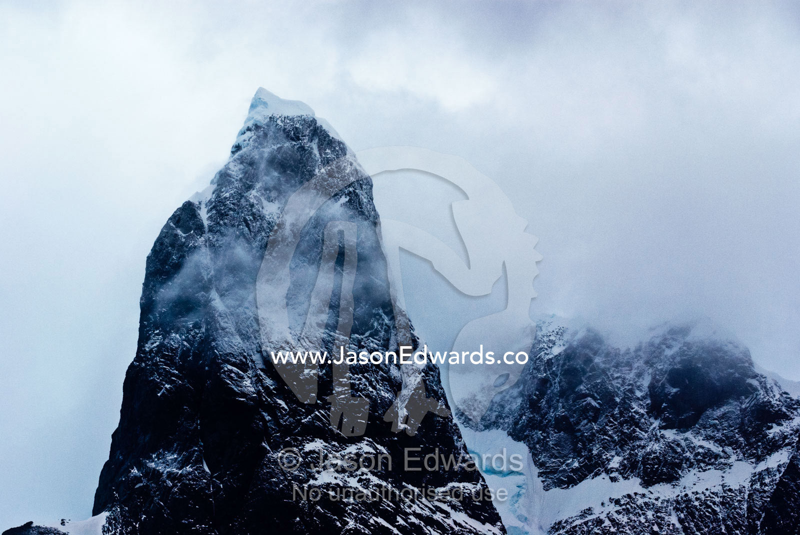 A dark brooding storm descends on a massive jagged mountain peak. Lemaire Channel, Antarctic Peninsula, Antarctica.