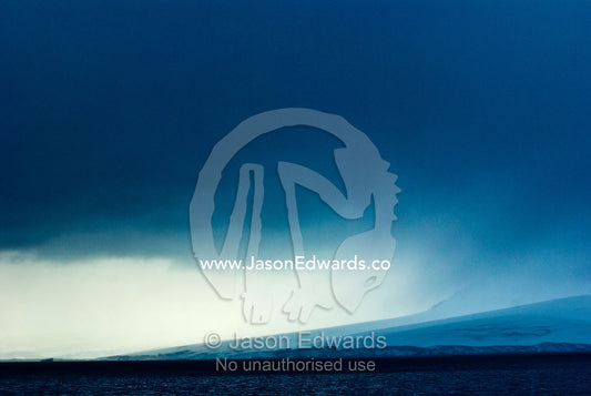 A menacing storm descends over a massive glacier running into the sea. Port Lockroy, Gerlache Strait, Antarctic Peninsula, Antarctica.
