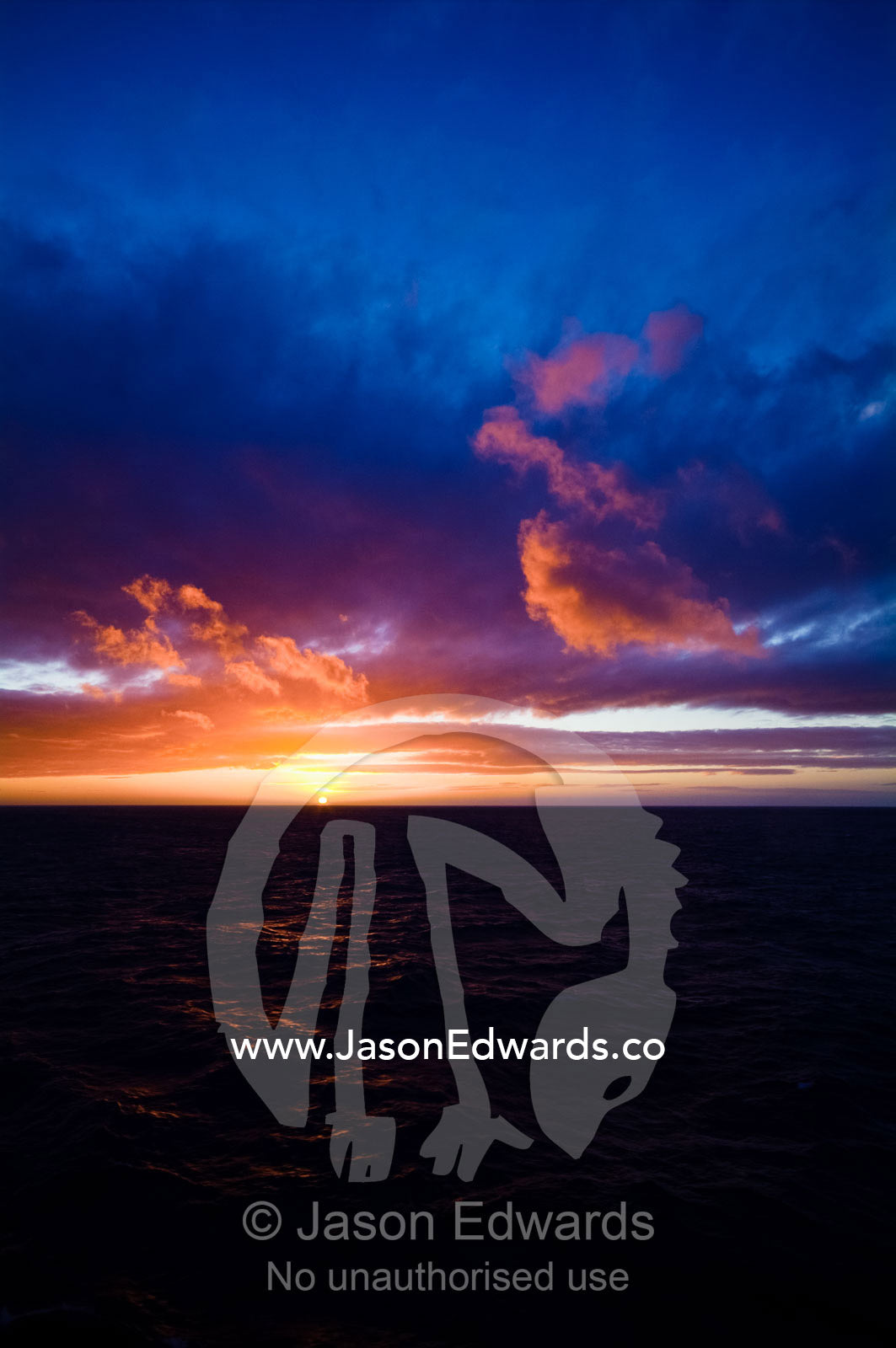 A flaming orange dawn over a distant ocean horizon in Antarctica. Bransfield Strait, Deception Island, South Shetland Islands, Antarctica.