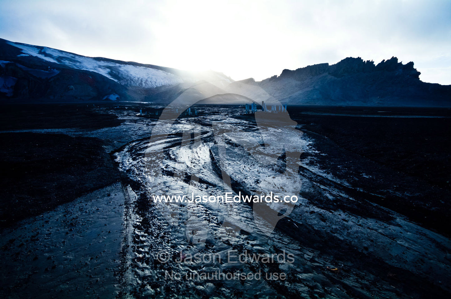Ice melt forms streams that carve through black volcanic sand beaches. Whalers Bay, Port Foster, Deception Island, South Shetland Islands, Antarctic Peninsula, Antarctica.