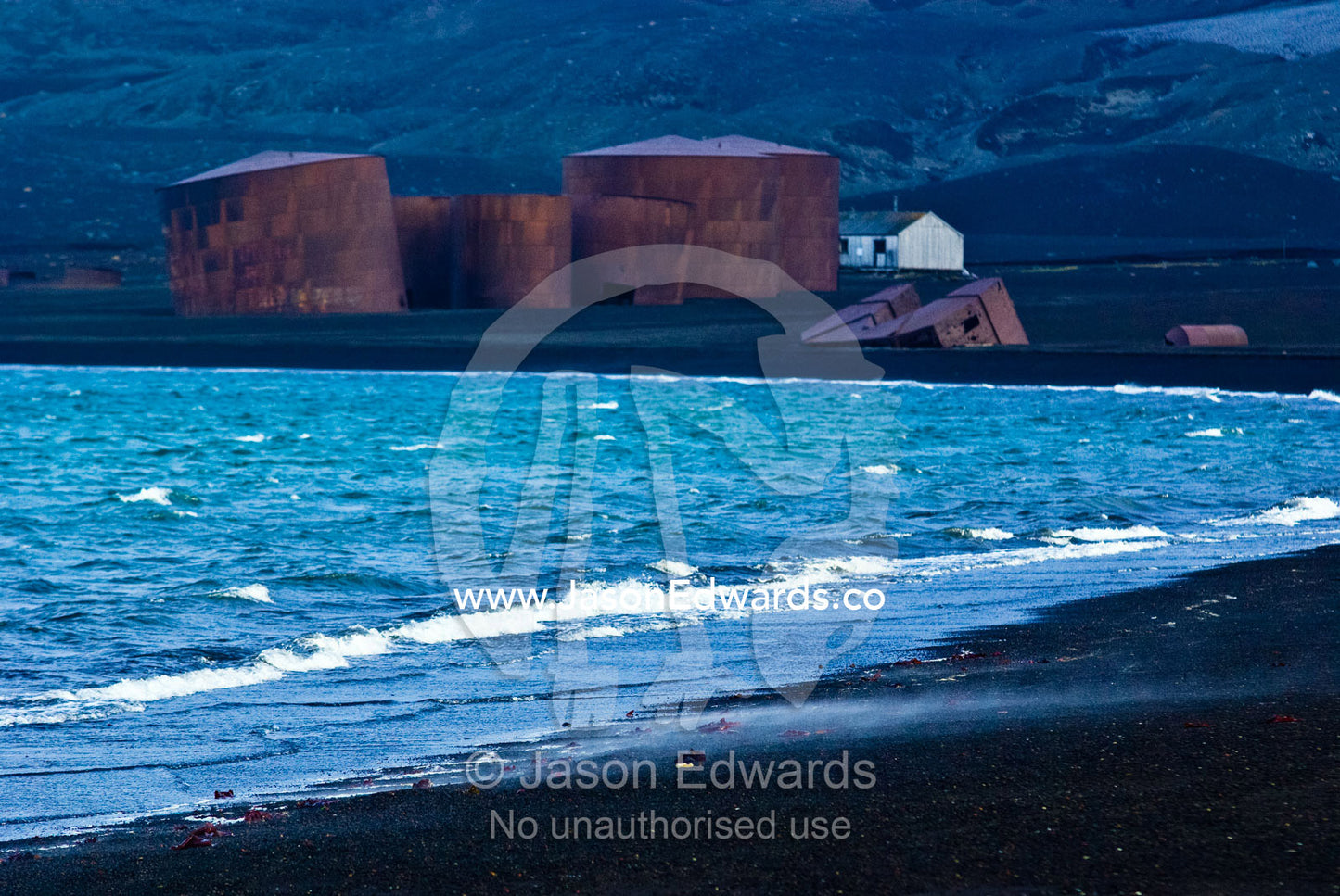 A geothermal steaming beach near abandoned whaling station oil tanks. Hektor Whaling Station, Whalers Bay, Port Foster, Deception Island, South Shetland Islands, Antarctic Peninsula, Antarctica.