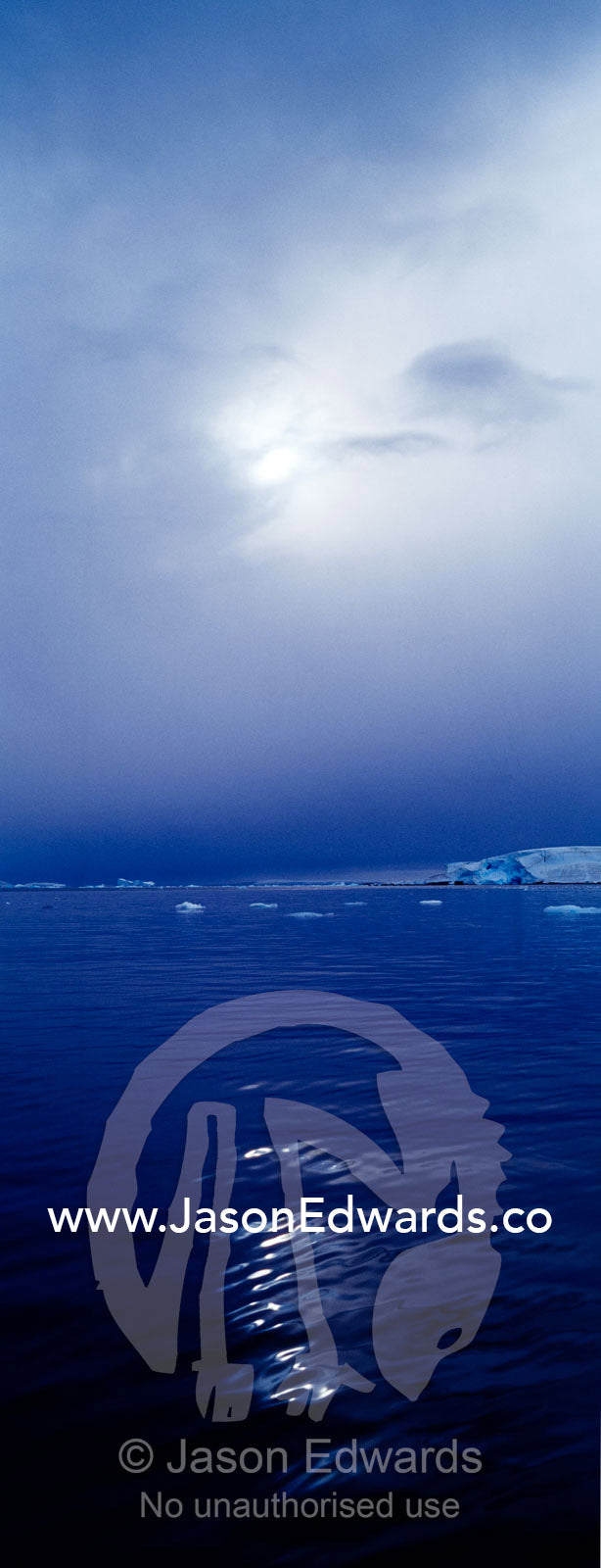 The sun casts ghostly reflected light over the surface of a calm sea. Fish Islands, The Minnows, Flounder Island, Crystal Sound, Antarctic Peninsula, Antarctic Circle, Antarctica.