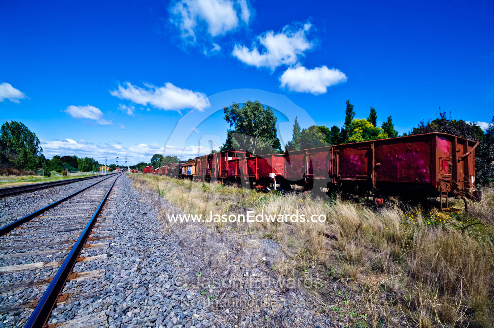 Antique train carriages rusting beside a rural railway track. Castlemaine, Victoria, Australia.
