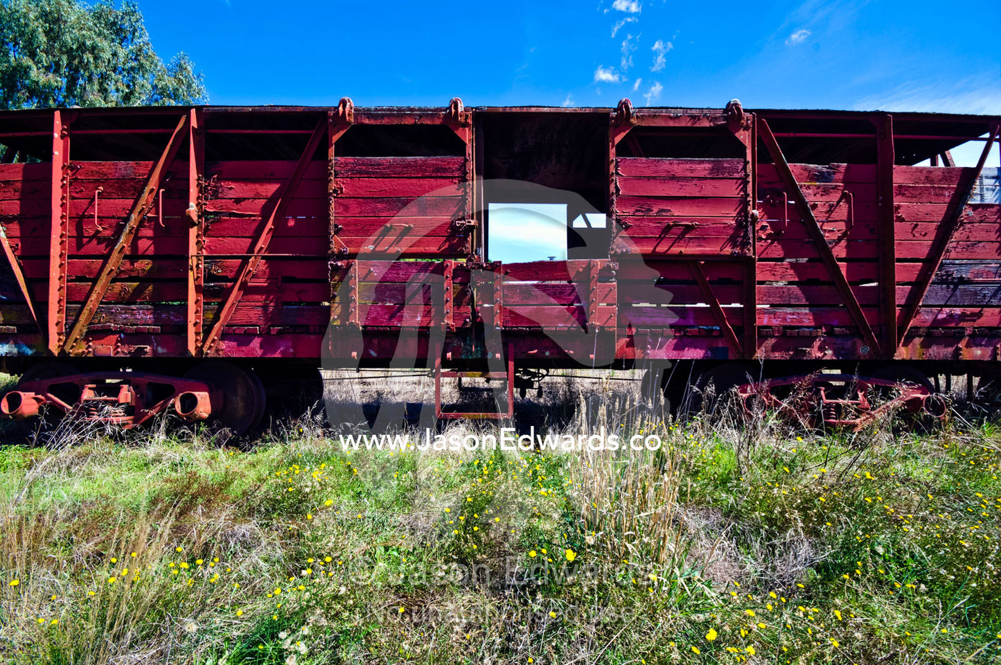 An antique train carriage rusting beside a rural railway track. Castlemaine, Victoria, Australia.