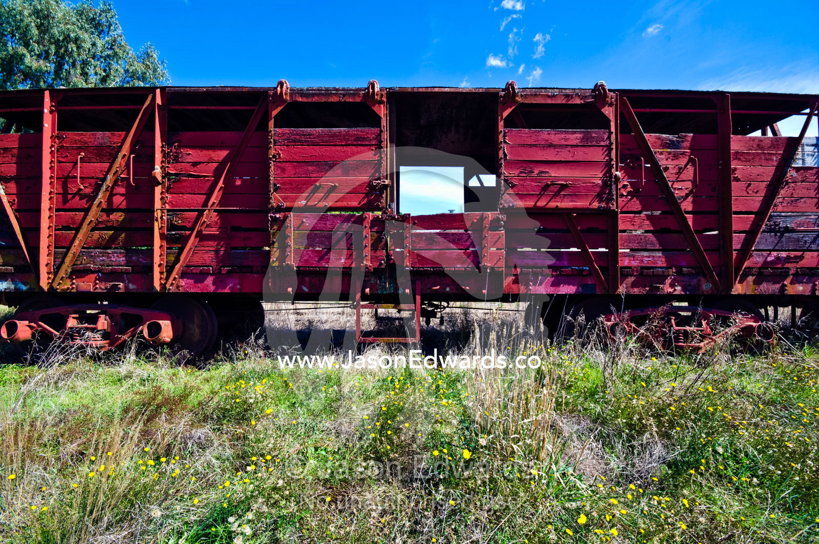 An antique train carriage rusting beside a rural railway track. Castlemaine, Victoria, Australia.