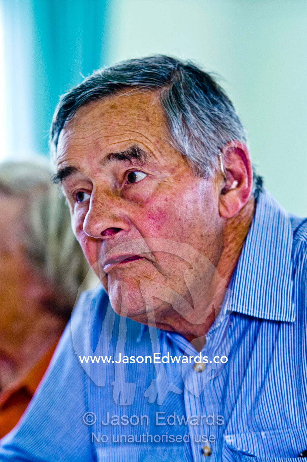 An elderly gentleman listens intently to a conversation over lunch. Castlemaine, Victoria, Australia.