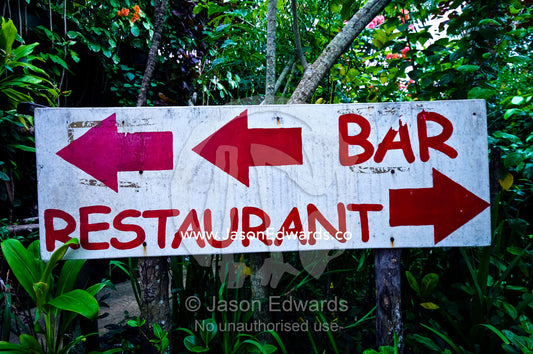A simple sign points in the direction of a bar and a restaurant. Port of Refuge, Neiafu, Vava'u Island Group, Pacific Ocean, Oceania, Kingdom of Tonga.