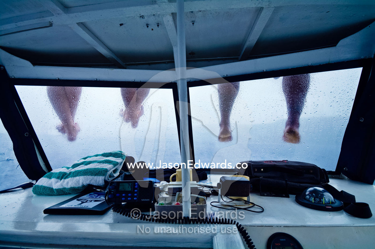 People sit on the roof of a motor boat to dangle their legs and feet. Port of Refuge, Neiafu, Vava'u Island Group, Pacific Ocean, Oceania, Kingdom of Tonga.