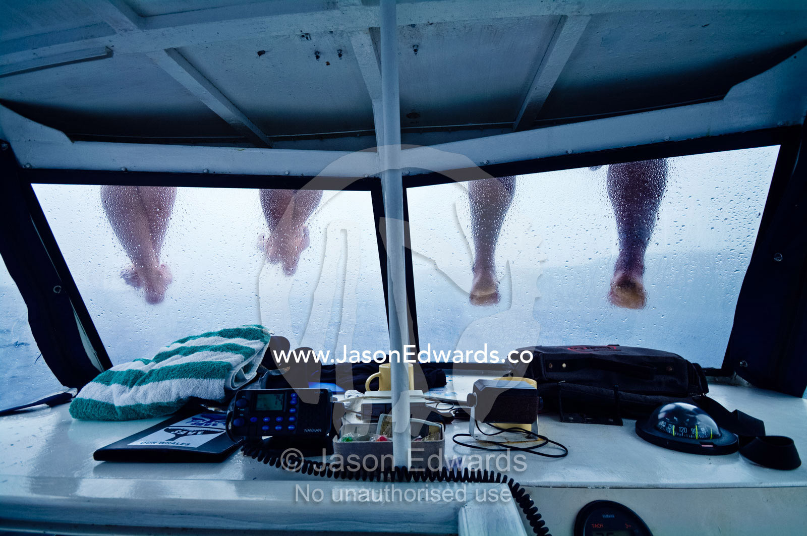 People sit on the roof of a motor boat to dangle their legs and feet. Port of Refuge, Neiafu, Vava'u Island Group, Pacific Ocean, Oceania, Kingdom of Tonga.