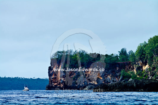 A tourist whale watching boat moored in the bay of a limestone island. Vava'u Island Group, Pacific Ocean, Oceania, Kingdom of Tonga.