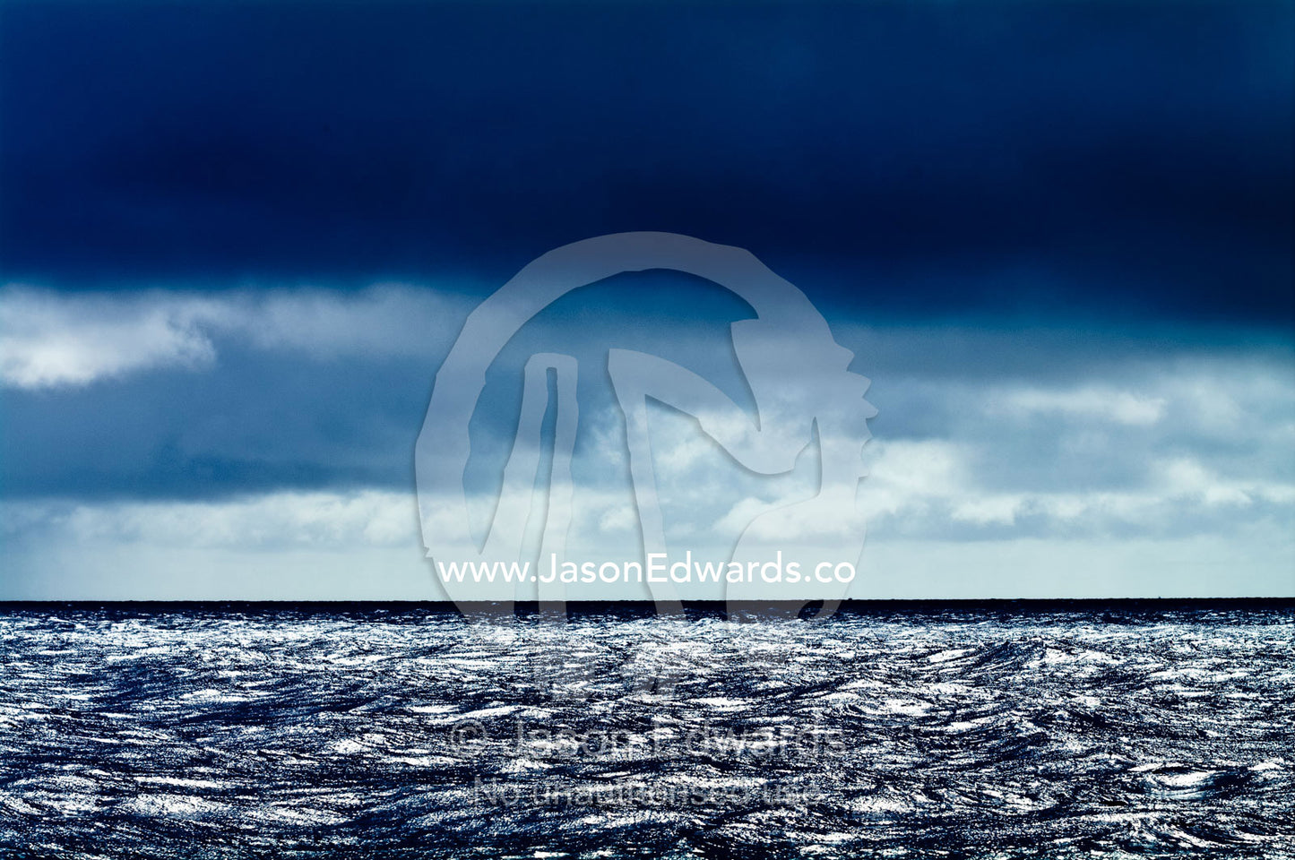 A dark, menacing storm descends over a calm silvery ocean surface. Vava'u Island Group, Pacific Ocean, Oceania, Kingdom of Tonga.