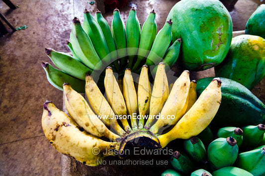 Bunches of ripe and unripe green bananas and papaya in a market. Utukalongalu Market, Port of Refuge, Neiafu, Vava'u Island Group, Pacific Ocean, Oceania, Kingdom of Tonga.