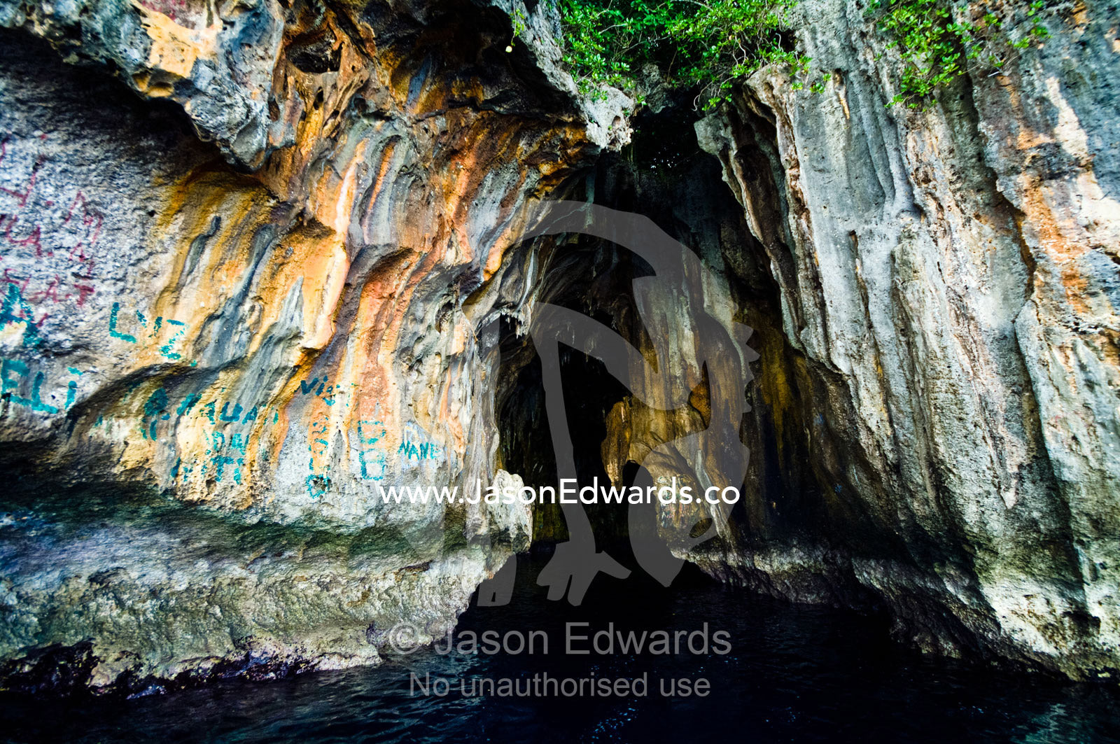 Graffiti near the entrance to a cave eroded in a limestone cliff. Swallows Cave, Vava'u Island Group, Pacific Ocean, Oceania, Kingdom of Tonga.