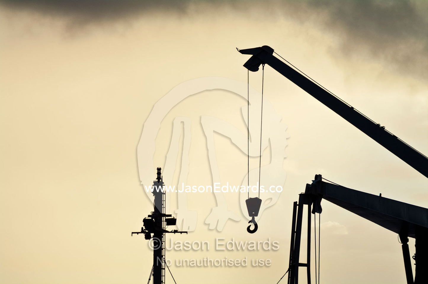A shipping port crane hook and boom hangs in the sky at sunset. Port of Refuge, Neiafu, Vava'u Island Group, Pacific Ocean, Oceania, Kingdom of Tonga.