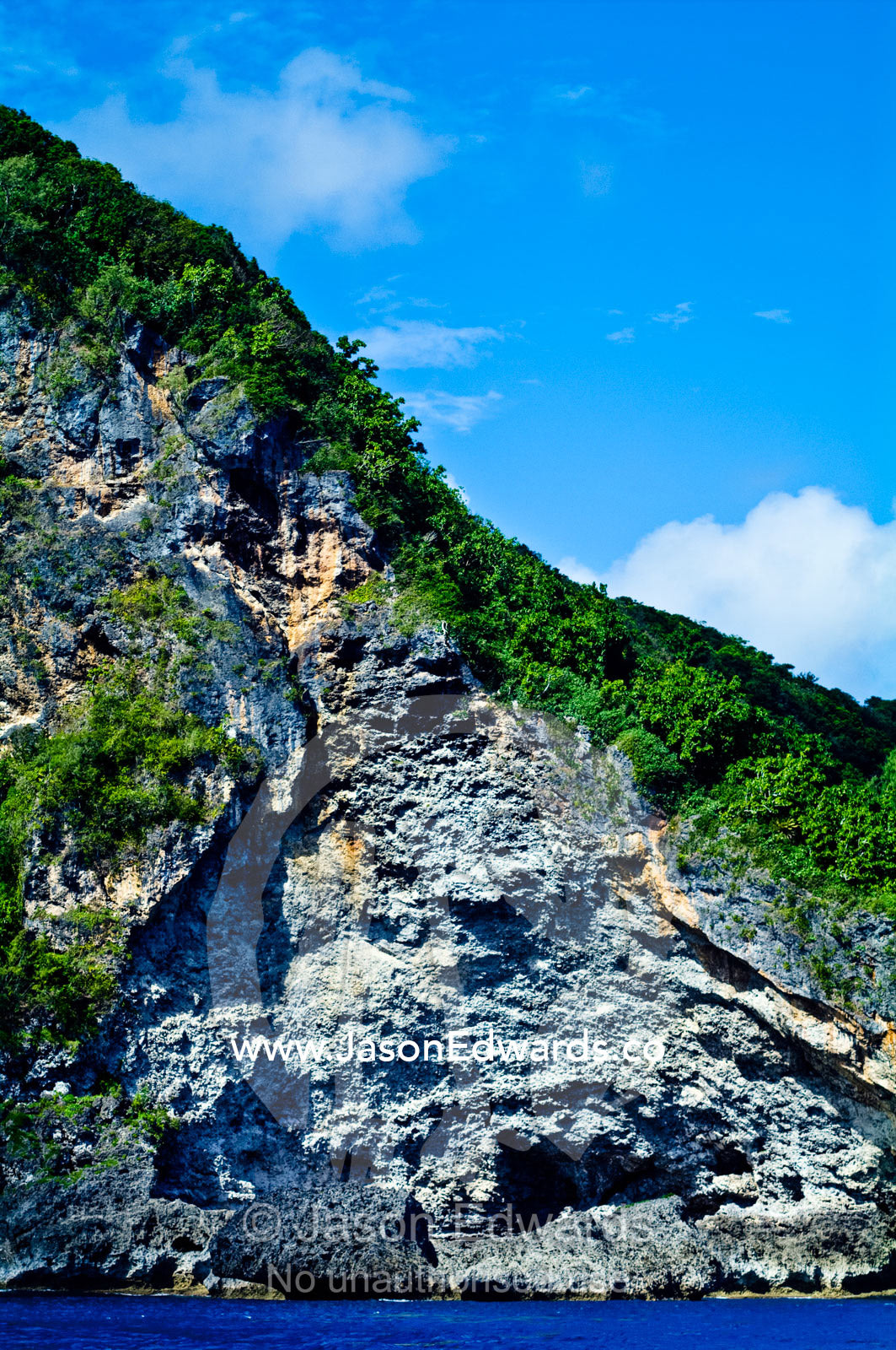A massive limestone cliff and rainforest rises from turquoise seas. Vava'u Island Group, Pacific Ocean, Oceania, Kingdom of Tonga.