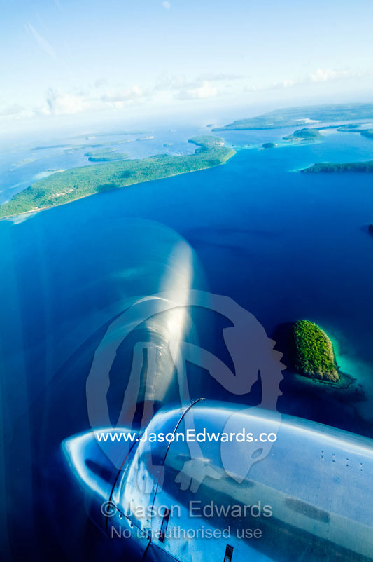 A chrome engine and propellor of a plane flying over tropical islands. Vava'u Island Group, Pacific Ocean, Oceania, Kingdom of Tonga.