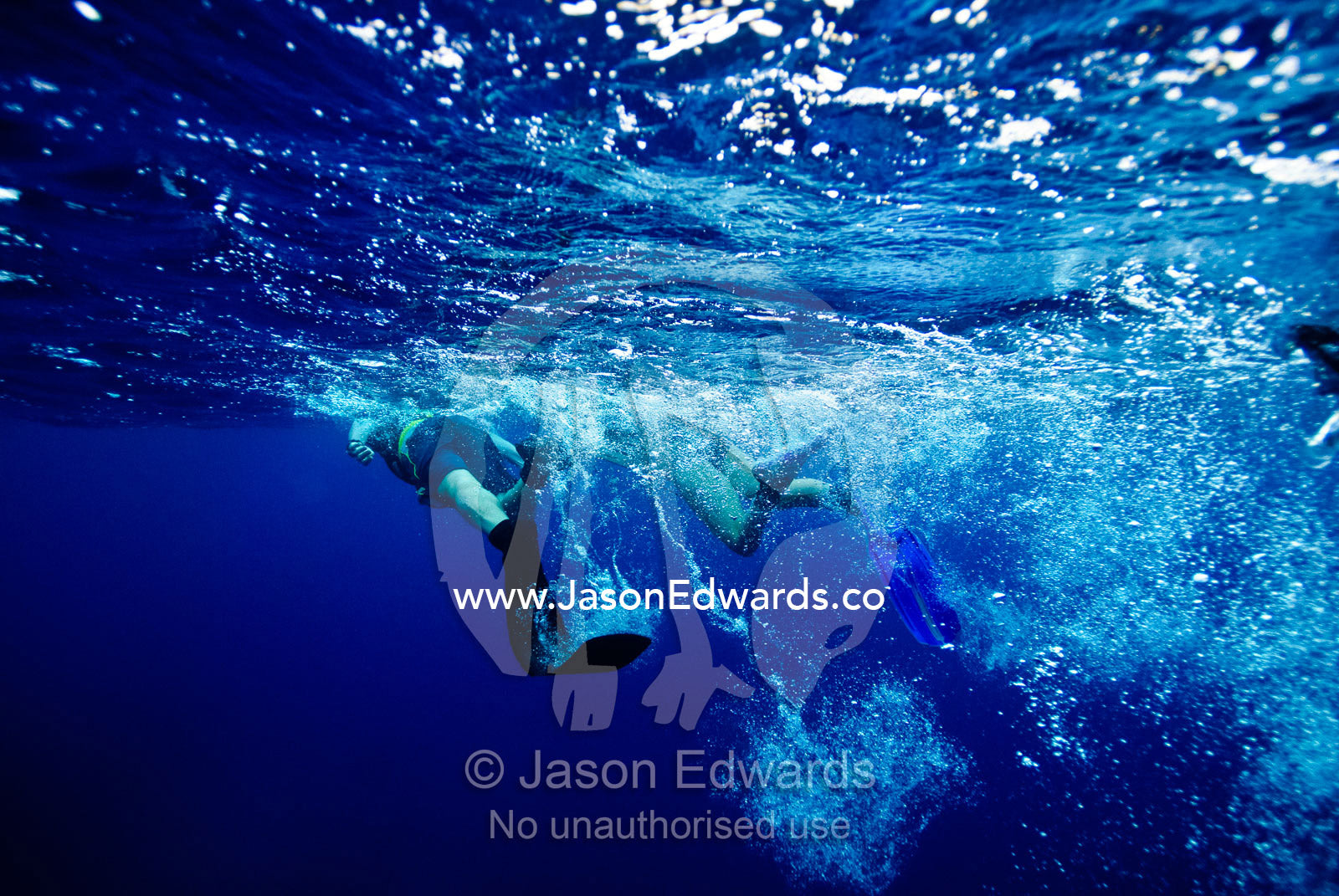 Snorkelers kick bubbles across the ocean surface using diving fins. Vava'u Island Group, Pacific Ocean, Oceania, Kingdom of Tonga.