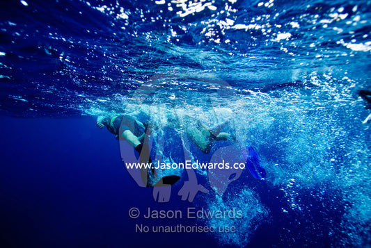 Snorkelers kick bubbles across the ocean surface using diving fins. Vava'u Island Group, Pacific Ocean, Oceania, Kingdom of Tonga.