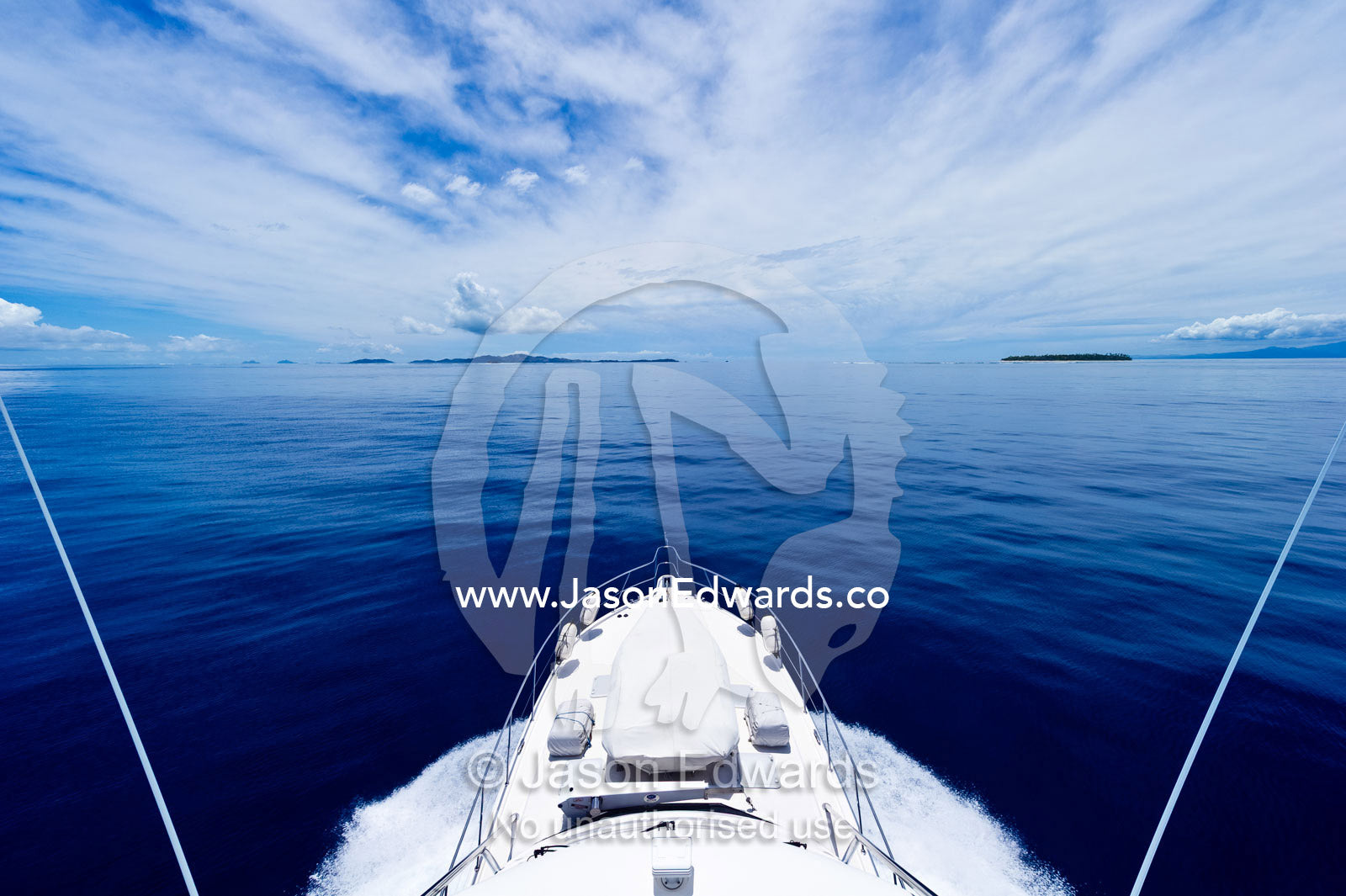 A luxury boat ploughs through a calm turquoise ocean in the Pacific. Nanuya Balavu Island, Yasawa Group, Pacific Ocean, Fiji Islands.
