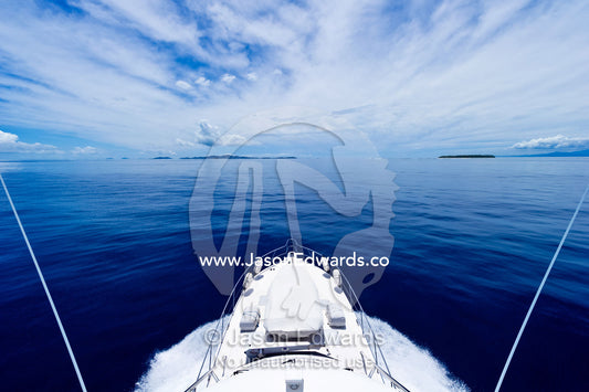 A luxury boat ploughs through a calm turquoise ocean in the Pacific. Nanuya Balavu Island, Yasawa Group, Pacific Ocean, Fiji Islands.